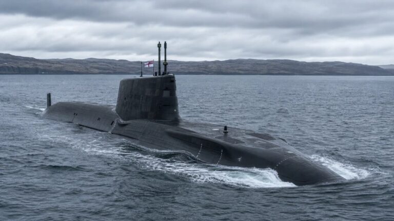 Long black submarine hull with a tall sail moored beside a concrete pier under a cloudy sky.
